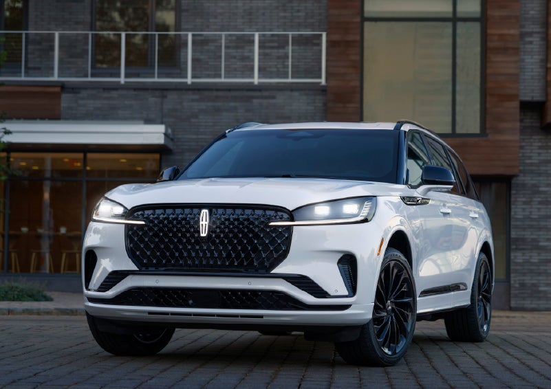 A 2026 Lincoln Aviator® Reserve model is shown with the available Jet Appearance Package parked near a restaurant. | Miller Lincoln in Saint Cloud MN