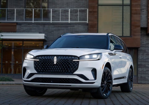 A 2026 Lincoln Aviator® Reserve model is shown with the available Jet Appearance Package parked near a restaurant. | Miller Lincoln in Saint Cloud MN