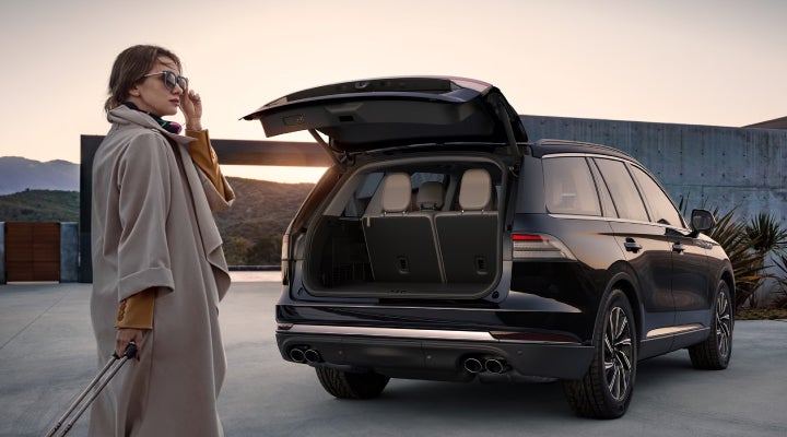 A woman approaches a 2026 Lincoln Aviator® SUV with its rear liftgate open. | Miller Lincoln in Saint Cloud MN