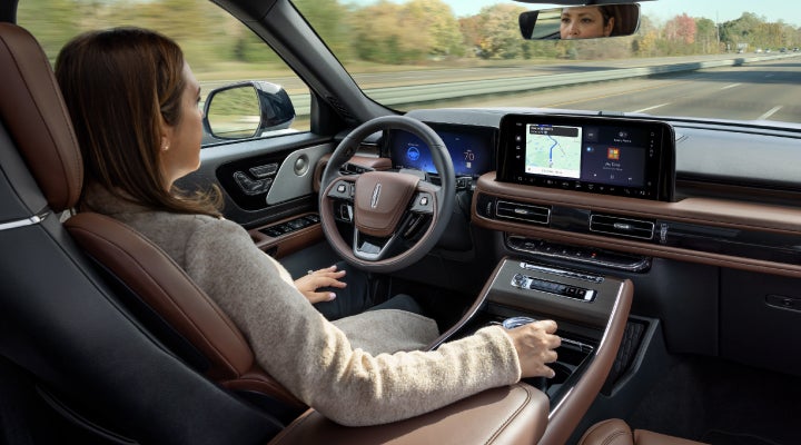 A 2026 Lincoln Aviator® SUV is being driven hands-free on a highway near a forest | Miller Lincoln in Saint Cloud MN