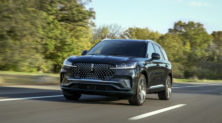 A 2026 Lincoln Black Label™ Aviator® SUV is being driven down a road lined with trees. | Miller Lincoln in Saint Cloud MN