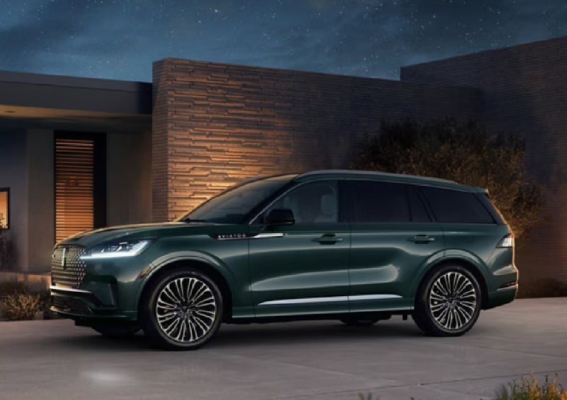 A green 2027 Lincoln Aviator® SUV is parked outside a contemporary home. | Miller Lincoln in Saint Cloud MN