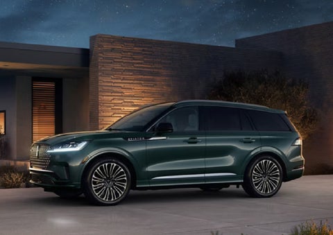 A green 2027 Lincoln Aviator® SUV is parked outside a contemporary home. | Miller Lincoln in Saint Cloud MN
