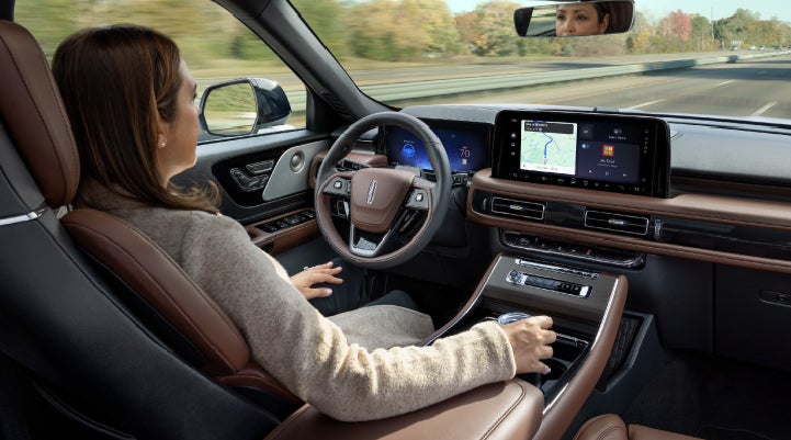 A 2027 Lincoln Aviator® SUV is being driven hands-free on a highway lined with trees. | Miller Lincoln in Saint Cloud MN