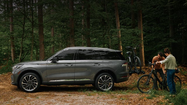 A father and son load e-bikes on a bike rack attached to a 2027 Lincoln Aviator® SUV. | Miller Lincoln in Saint Cloud MN