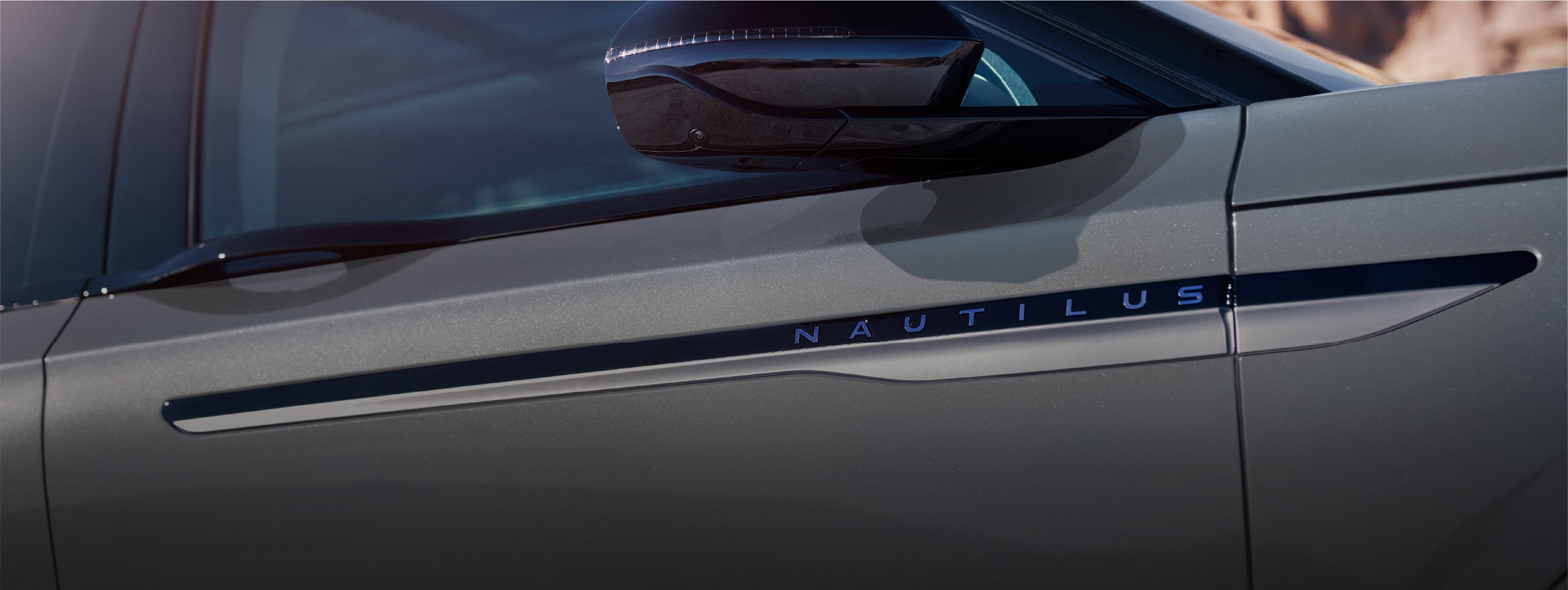 A close-up of the 2026 Lincoln Nautilus® Reserve Hybrid exterior showing the front door accent and sculpted body panel beneath the side mirror.